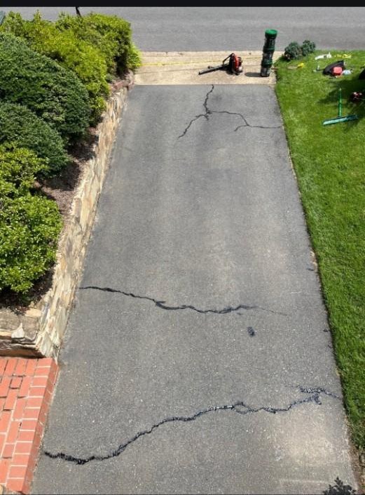 Driveway before sealcoating, with visible cracks running across the asphalt